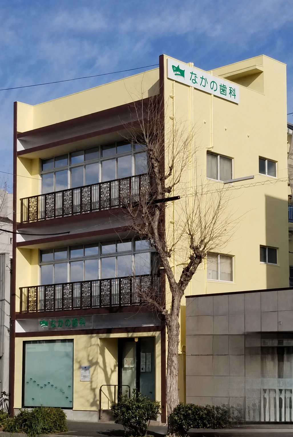 遮熱ミラーフィルム施工後の2・3階窓を含む、外壁・看板改修後のなかの歯科様の建物全景