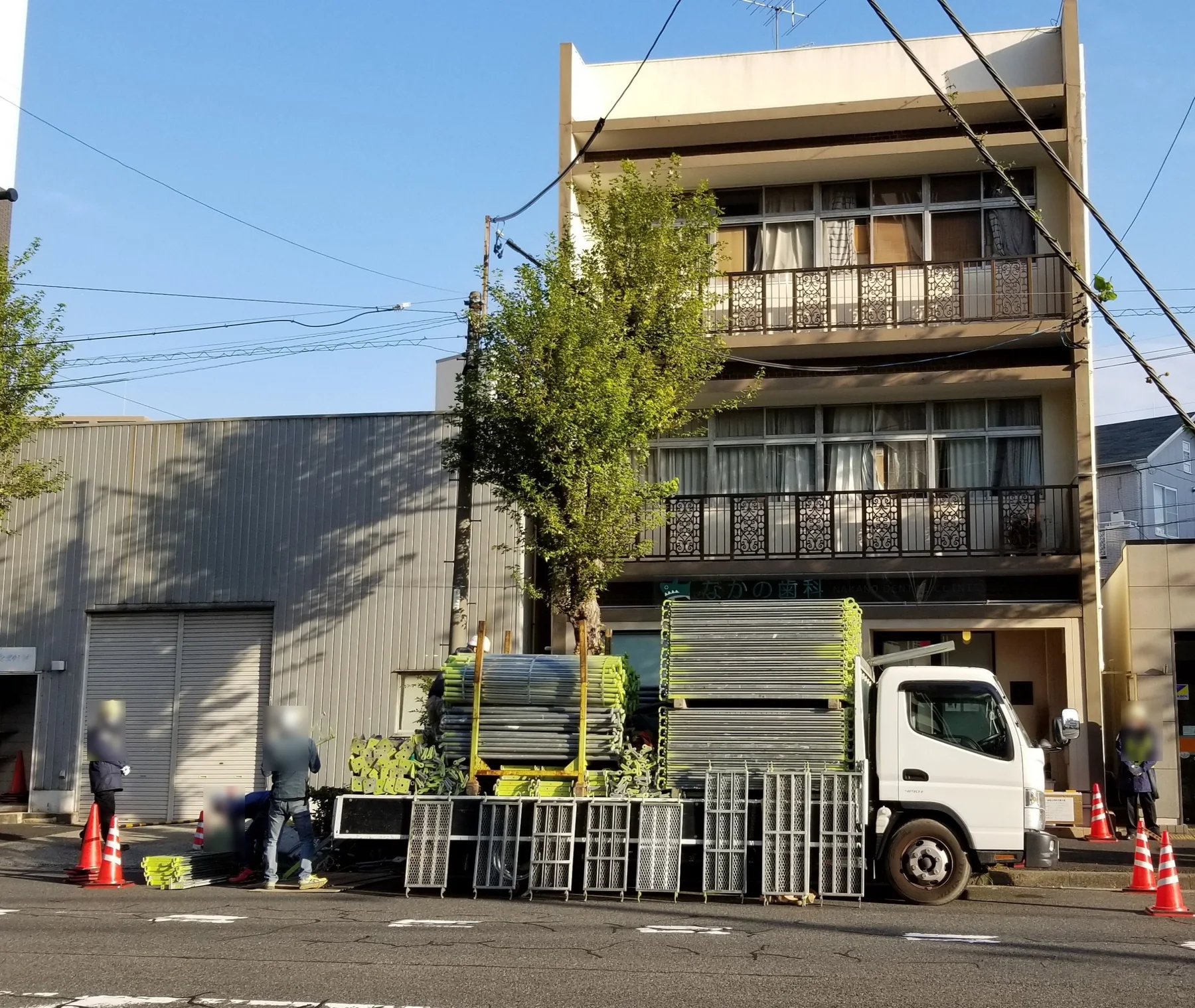 道路側で交通誘導員を配置し、足場材を搬入している様子