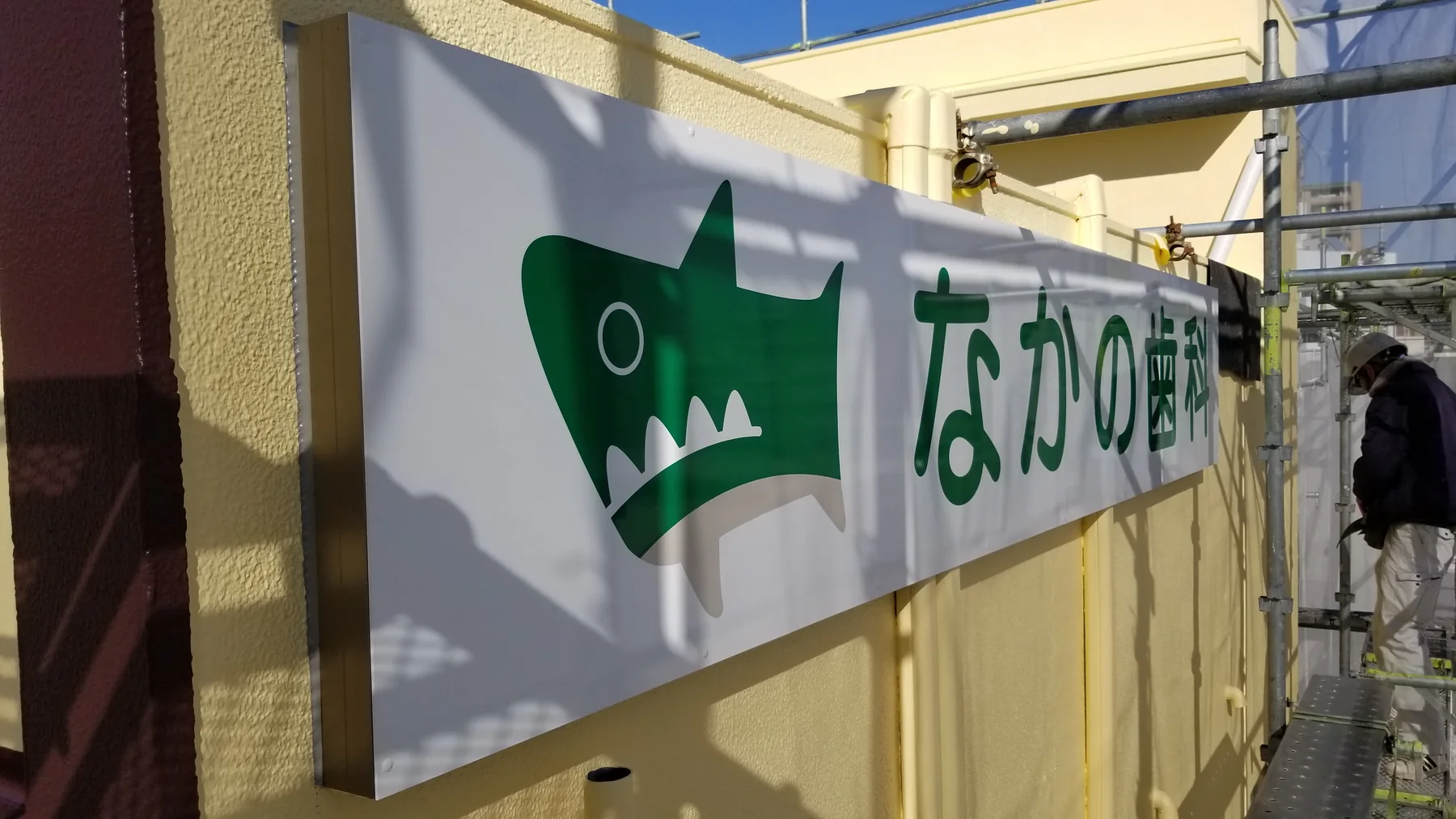 アルミ下地枠に新設した白地に緑色のなかの歯科看板