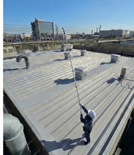 特殊高所カメラをポール先端まで伸ばし足場なしで屋根を点検する作業員