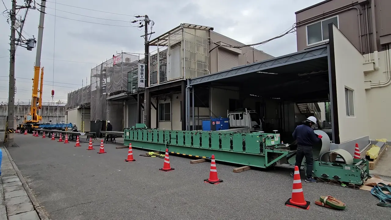 屋根材の現場成形動画の一場面。地上に設置した長尺屋根材の成形機
