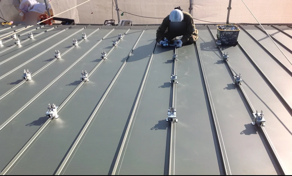 立平葺きのハゼへ太陽光架台用のつかみ金具を取り付けている状況